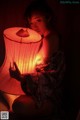 A woman sitting on the floor holding a red lamp.