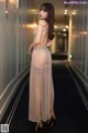 A woman in a sheer dress standing in a hallway.