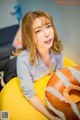 A woman sitting on a yellow bean bag chair holding a donut.