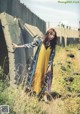 A woman in a yellow dress standing in a field.