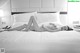 A naked woman laying on a bed in a hotel room.