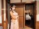 A woman in a kimono standing in front of a door.