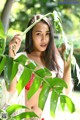 A woman in a red bikini posing in front of a tree.