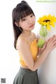 A woman in a yellow top holding a sunflower.