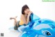 A woman sitting on top of an inflatable blue whale.