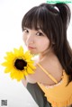 A woman holding a sunflower in her hand. 