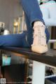 A woman sitting on top of a table wearing a pair of shoes.