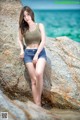 A woman sitting on a rock by the ocean.