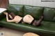 A woman laying on a green couch wearing black stockings and high heels.