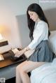 A woman sitting on a bed using a laptop computer.