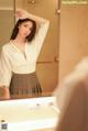 A woman standing in front of a mirror in a bathroom.