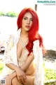 A woman with long red hair sitting on a bench.