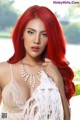 A woman with long red hair wearing a white dress.