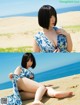 A woman sitting on top of a sandy beach next to the ocean.