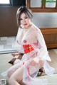 A woman in a white and red lingerie sitting on the floor.