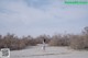 A woman in a white dress walking on a sandy beach.