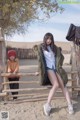 A woman sitting on top of a wooden fence next to a child.