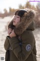 A woman wearing a green parka with a fur hood.