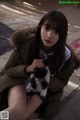 A woman sitting on the ground holding a black and white cat.