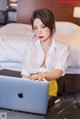 A woman sitting at a table with a laptop computer.