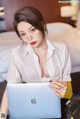 A woman sitting on a bed using a laptop computer.