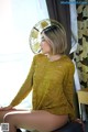 A woman sitting on top of a stool next to a window.