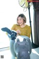 A woman sitting on top of a stuffed hippo next to a fan.