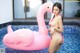 A woman in a bikini standing next to a pink flamingo float.