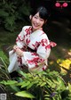 A woman in a red and white kimono sitting in a garden.