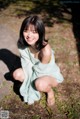 A woman crouching down on the ground in a park.