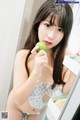 A woman holding a green apple in front of a mirror.