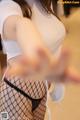 A woman in a white shirt and black fishnet stockings.