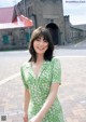 A woman in a green dress standing in front of a building.