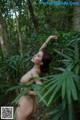 A naked woman standing in the middle of a forest.