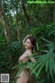 A naked woman standing in the middle of a forest.