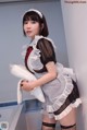 A woman in a maid outfit holding a pillow.