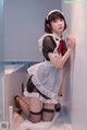 A woman in a maid outfit leaning against a wall.