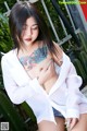 A woman with a tattoo on her chest is posing for the camera.