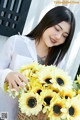 A woman holding a basket full of sunflowers.