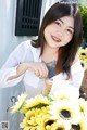 A woman holding a bunch of sunflowers in front of a house.