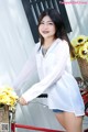 A woman standing next to a red bike with a basket of flowers.