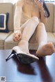 A woman sitting on a couch holding a pair of shoes.