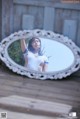 A woman in a white bodysuit is reflected in a mirror.