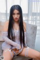 A woman in a white lingerie sitting on a couch.