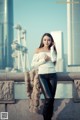 A woman in a white sweater and black leather pants posing for a picture.