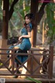 A woman in a blue dress sitting on a wooden bridge.