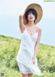 A woman in a white dress and straw hat standing in a field.