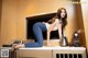 A woman sitting on top of a counter next to a coffee maker.