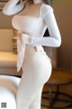 A woman in a white bodysuit posing on a bed.