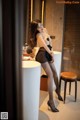 A woman in black stockings and high heels posing in front of a mirror.